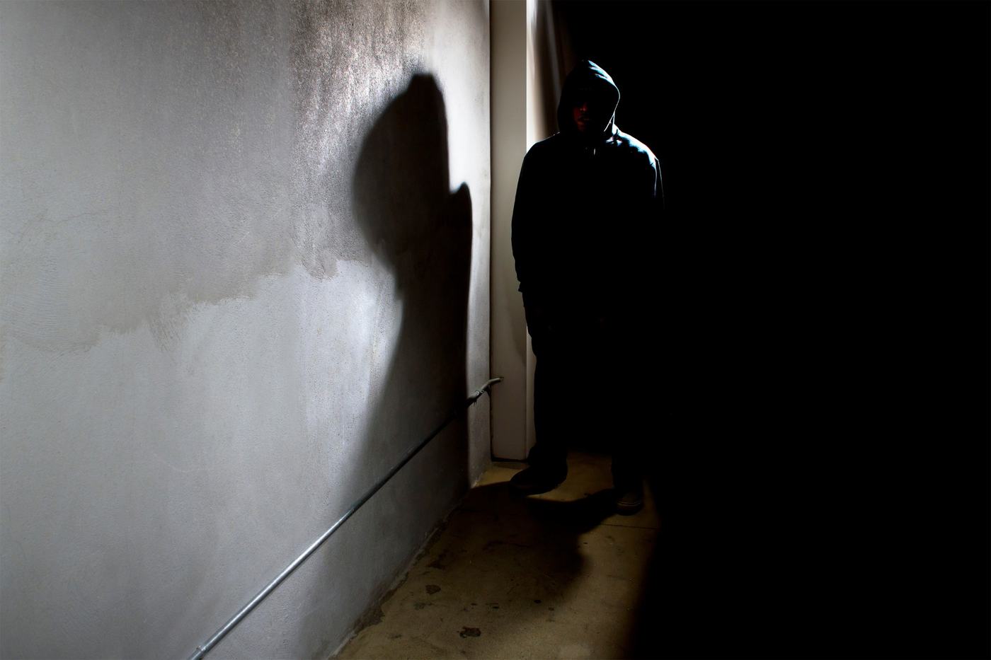 Person i hættetrøje står i en mørk gang – mørketid er indbrudstid